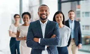 Confident corporate leader standing with arms crossed in front of a diverse team