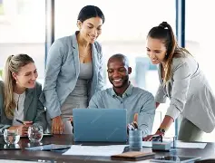 Team collaborating around a laptop in an office meeting
