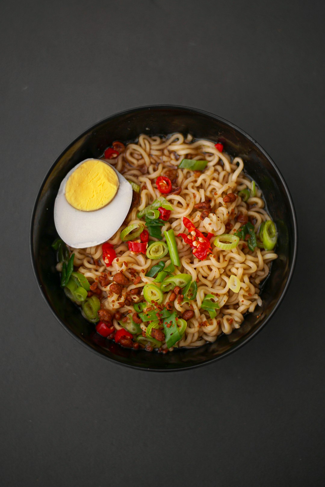 A bowl of Japanese ramen topped with a halved egg, chili and scallions, the kind of dish that hides fish-based dashi