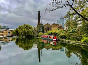 A canal boat gliding along London's Regent's Canal towpath lined with greenery