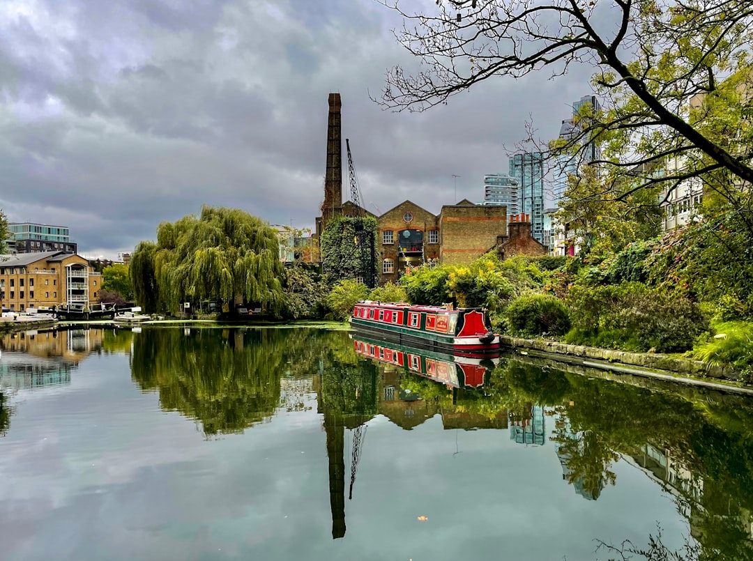 A canal boat gliding along London's Regent's Canal towpath lined with greenery