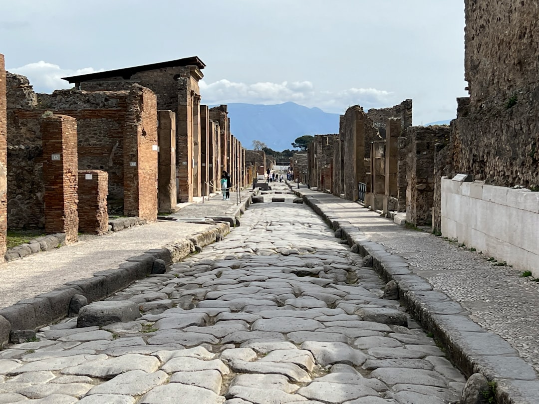 A cobblestone Roman street lined with the brick ruins of ancient apartment blocks at Ostia Antica