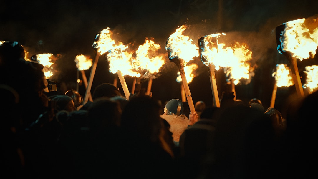 A crowd carrying flaming torches through the streets at night, similar to Edinburgh's Torchlight Procession