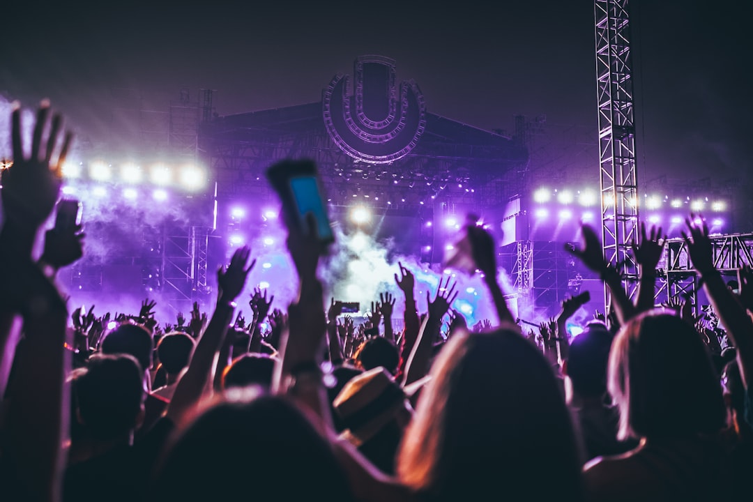 A crowd with raised hands at a night concert with stage lights, evoking the Yasalam after-race shows