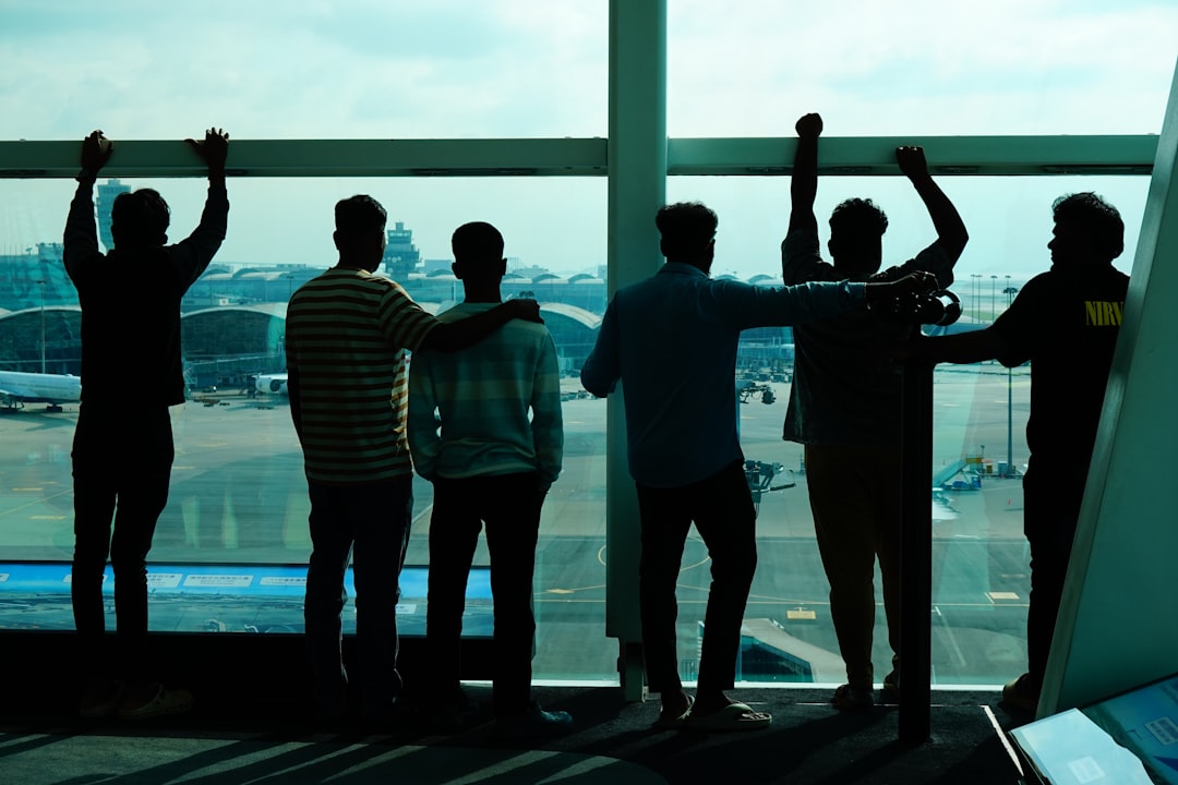 A group of student travellers looking out an airport window at planes on the tarmac