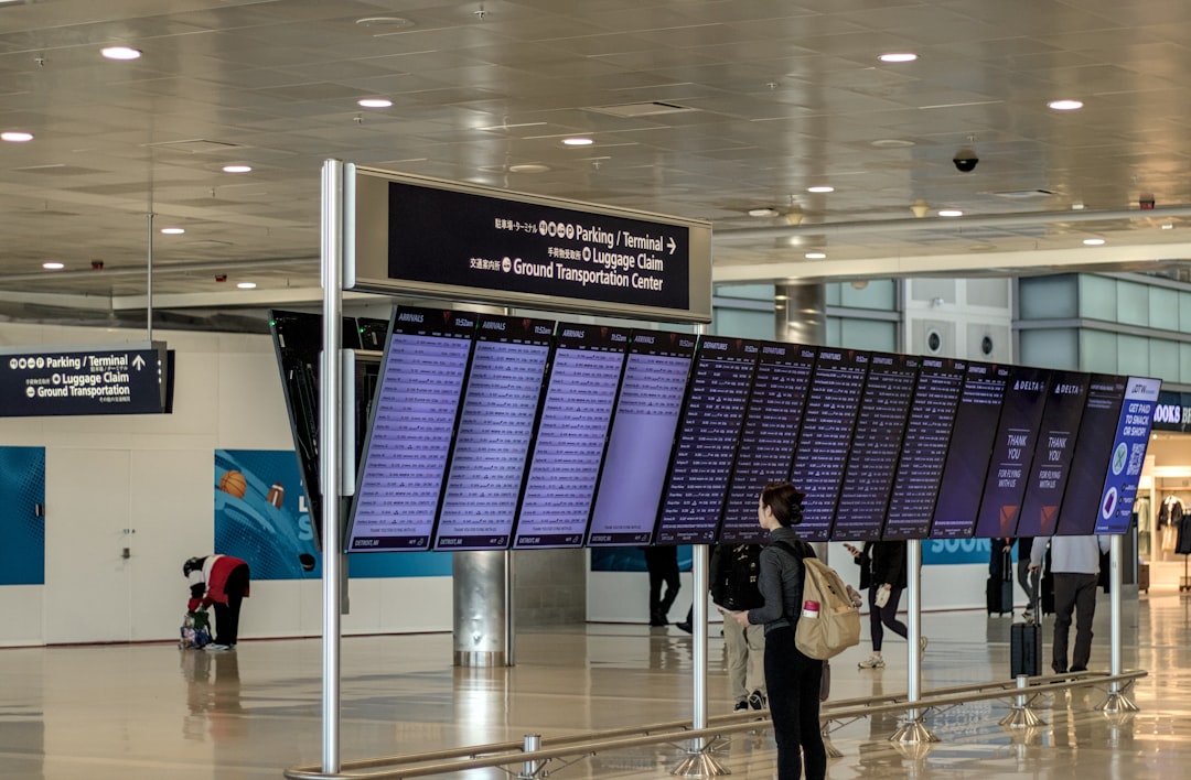 A traveller with a backpack studying a large airport flight information display board