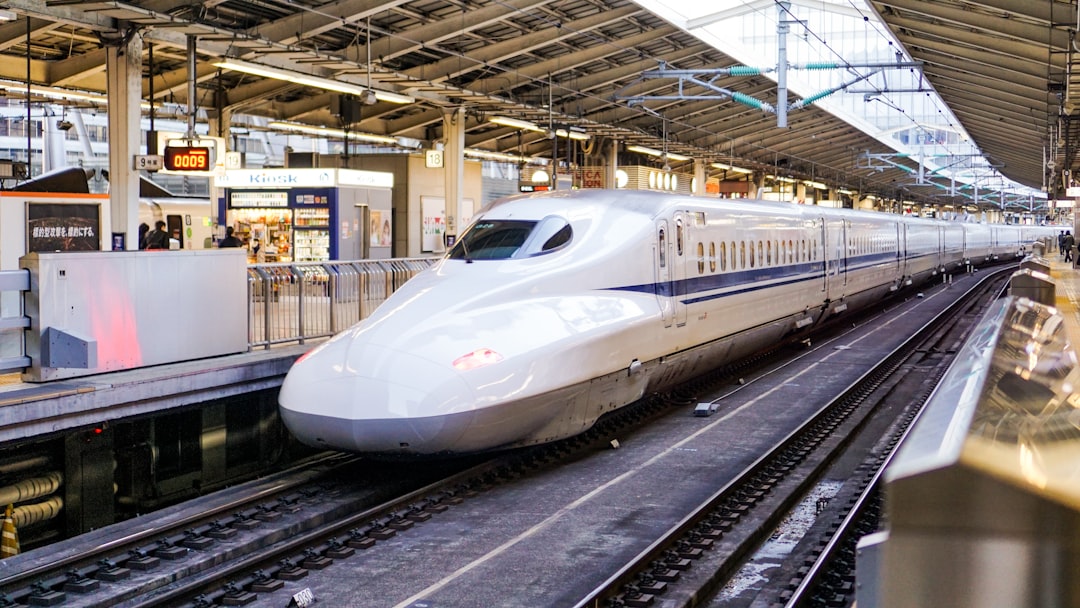 A white Shinkansen bullet train arriving at a Japanese railway station platform