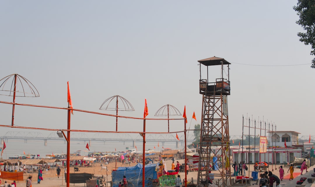 Crowded riverside ghats with watchtower and flags at Ayodhya during a festival