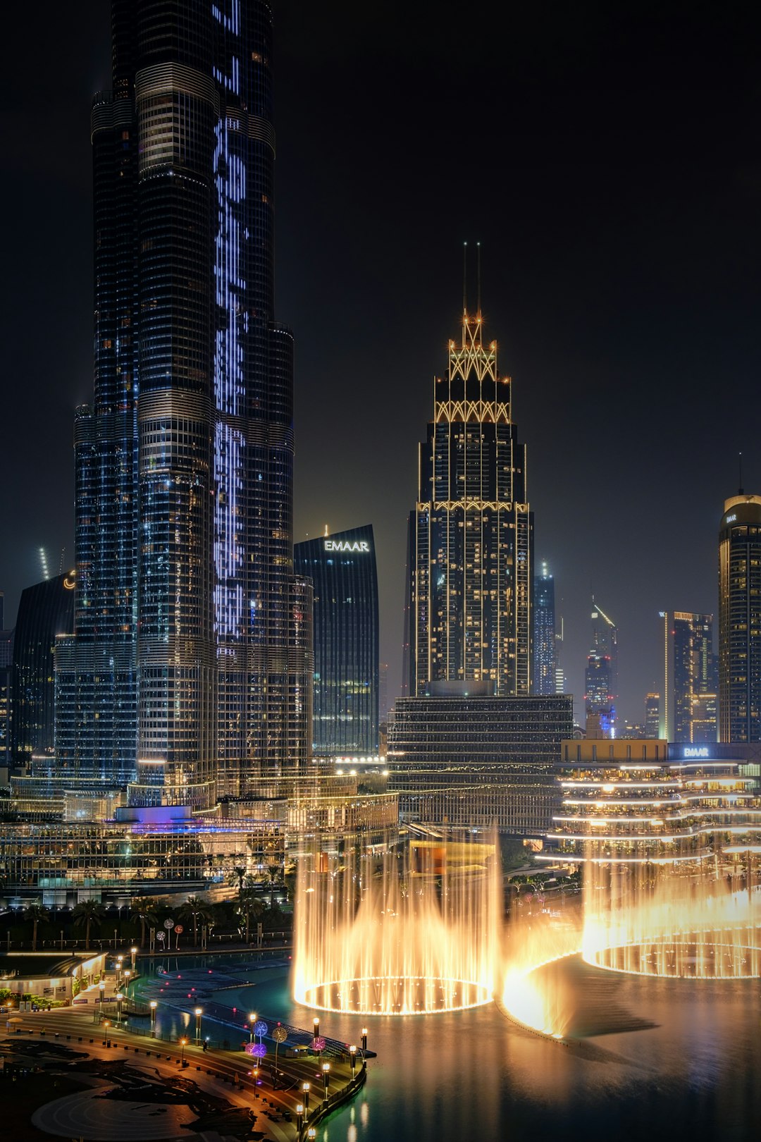 Dubai Mall fountain and Burj Khalifa skyline lit up at night, viewed from a restaurant table