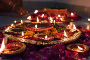 Lit clay diya oil lamps on a decorative tray surrounded by flower petals for Diwali