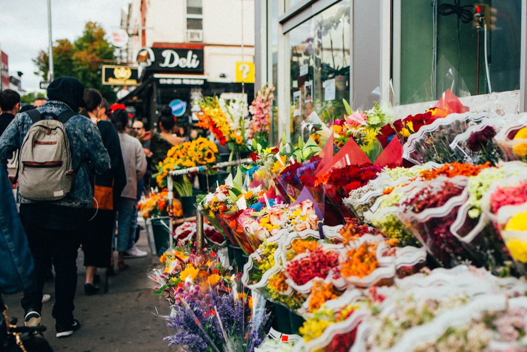Shoppers browsing colourful flower stalls on a London street market