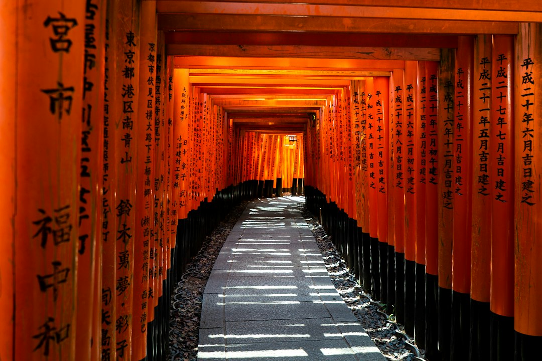 Stone path through a tunnel of orange torii gates at Fushimi Inari, Kyoto, Japan
